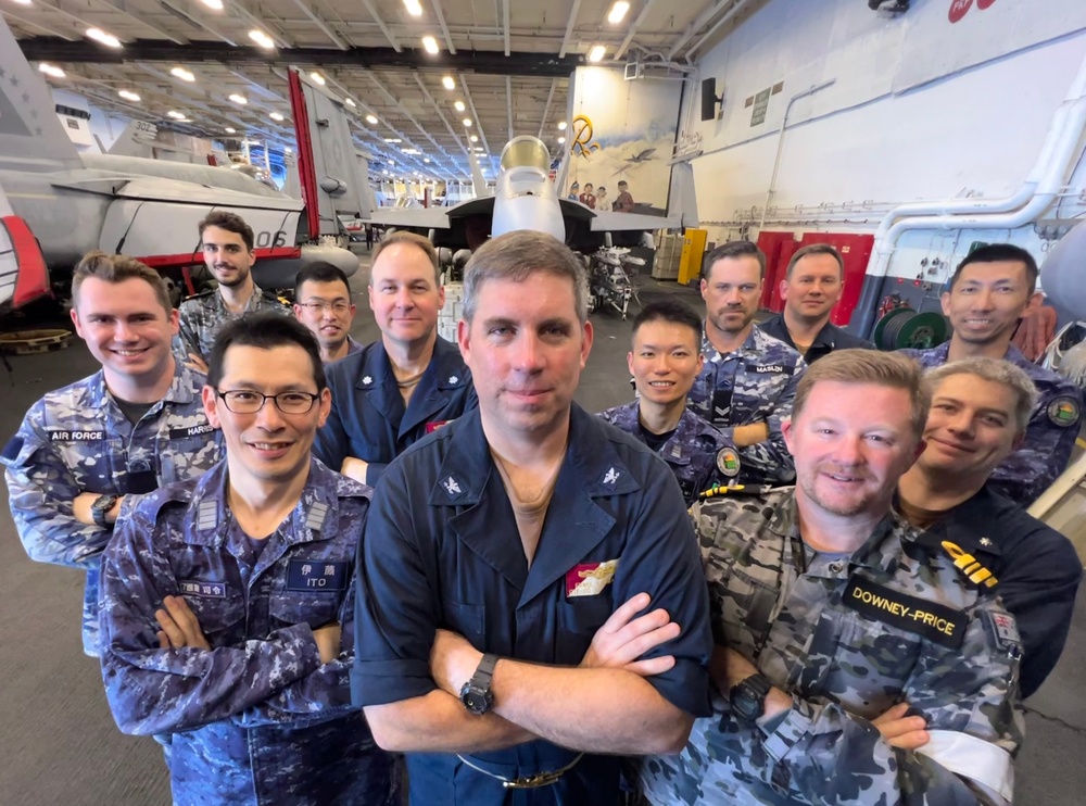Carrier Strike Group 5, Japan Maritime Self-Defense Force, Royal Australian Navy, and Royal Australian Air Force information warfare leaders and specialists pose for group photo aboard USS Ronald Reagan