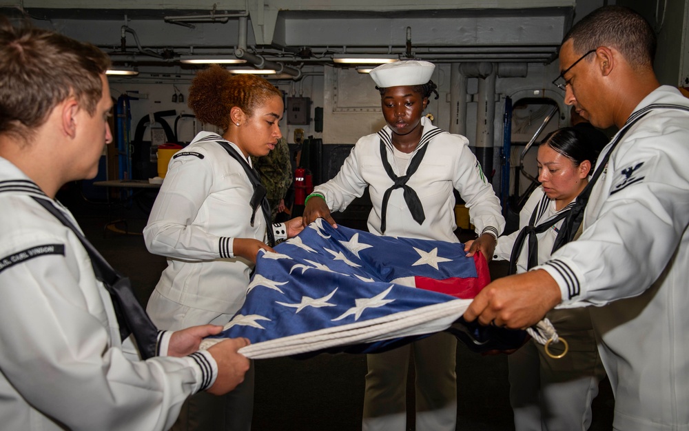 Sailors fold the flag aboard USS Carl Vinson