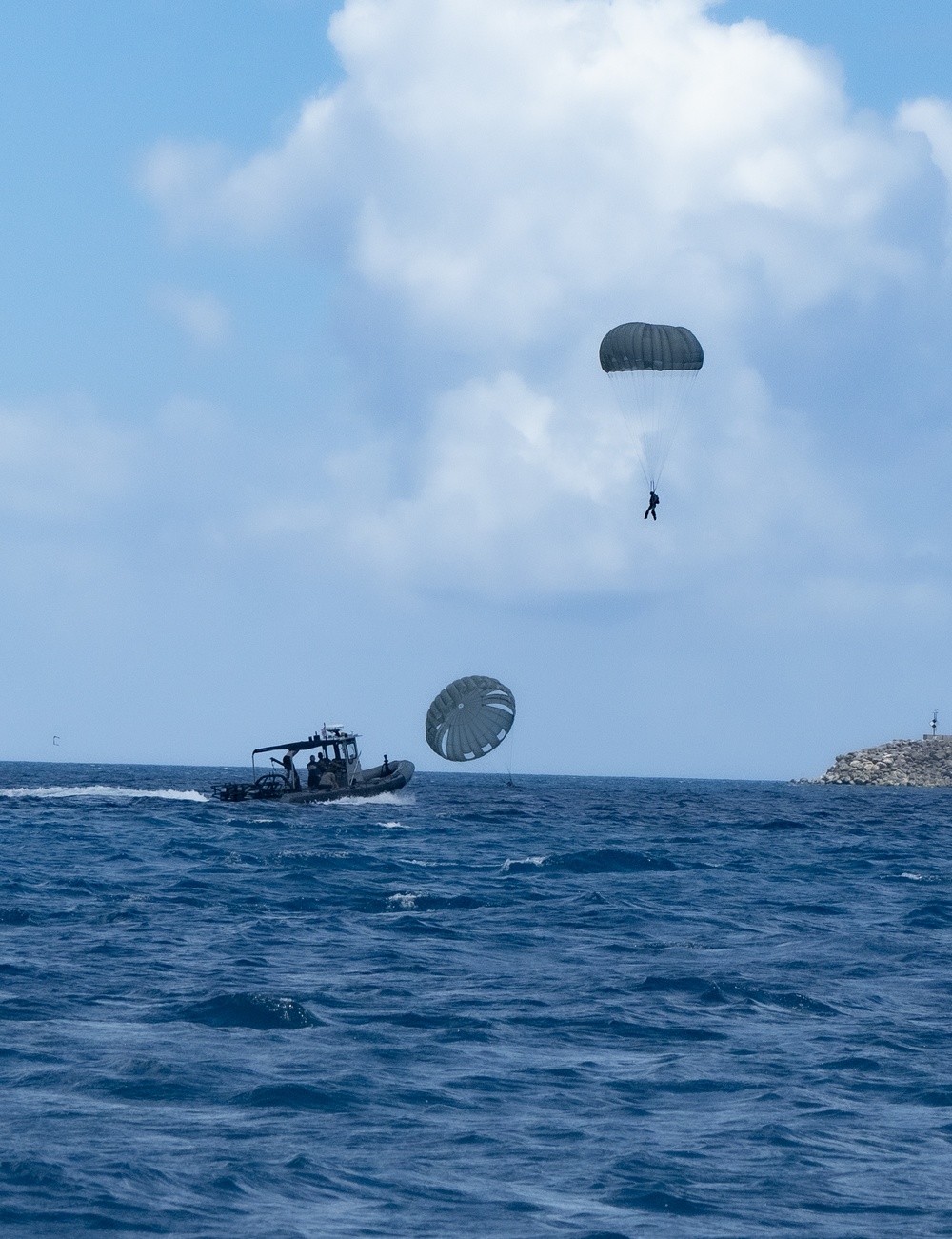 EOD sailors execute a water jump over Guam, landing in Apra Harbor