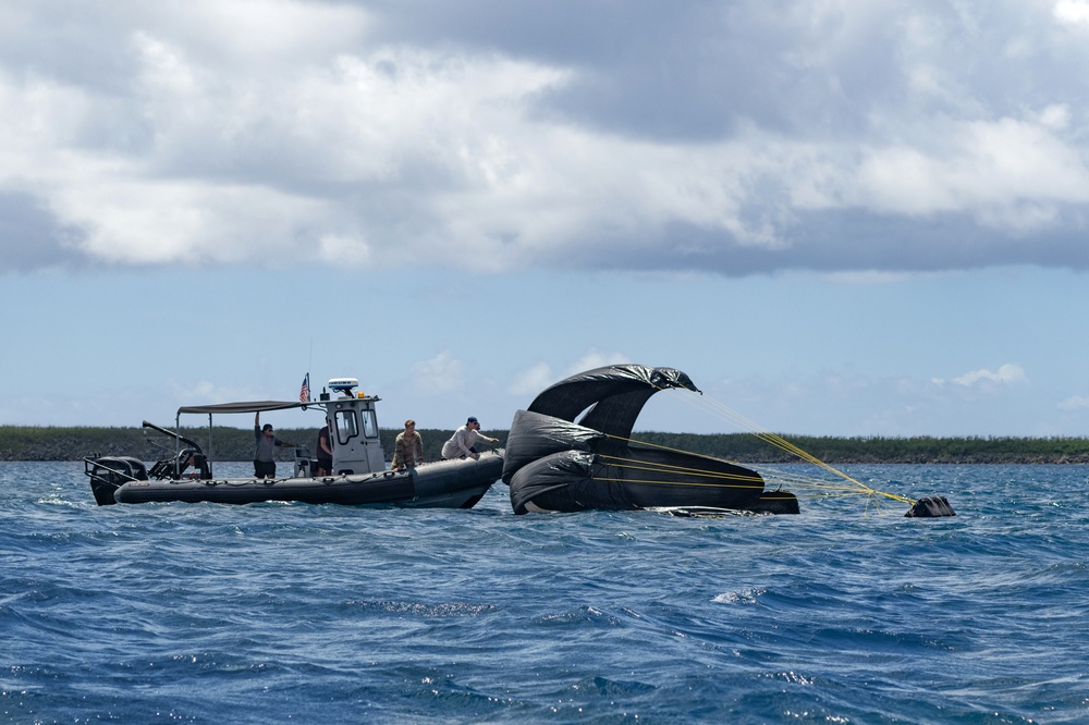 Team members collect cargo dropped from a C-2 aircraft into Apra Harbor during a training event