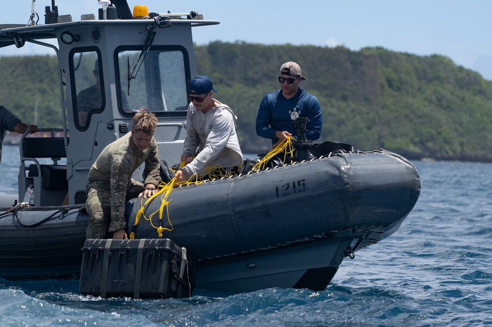 Team members collect cargo dropped from an aircraft as a part of static line jump training in Apra Harbor