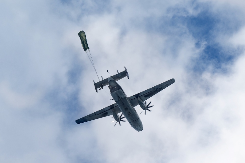 Sailors with EODMU5 jump out of a C-2 aircraft during a static line water jump over Guam