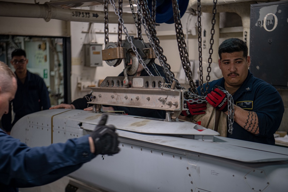 Sailors Hoist An Ordnance Shell