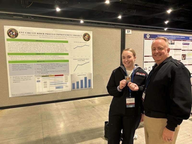 Hospital Corpsman 2nd Class Miranda Parkhurst receives coin from Rear Admiral Darin Via during the 2024 Association of Military Surgeons of the United States Conference