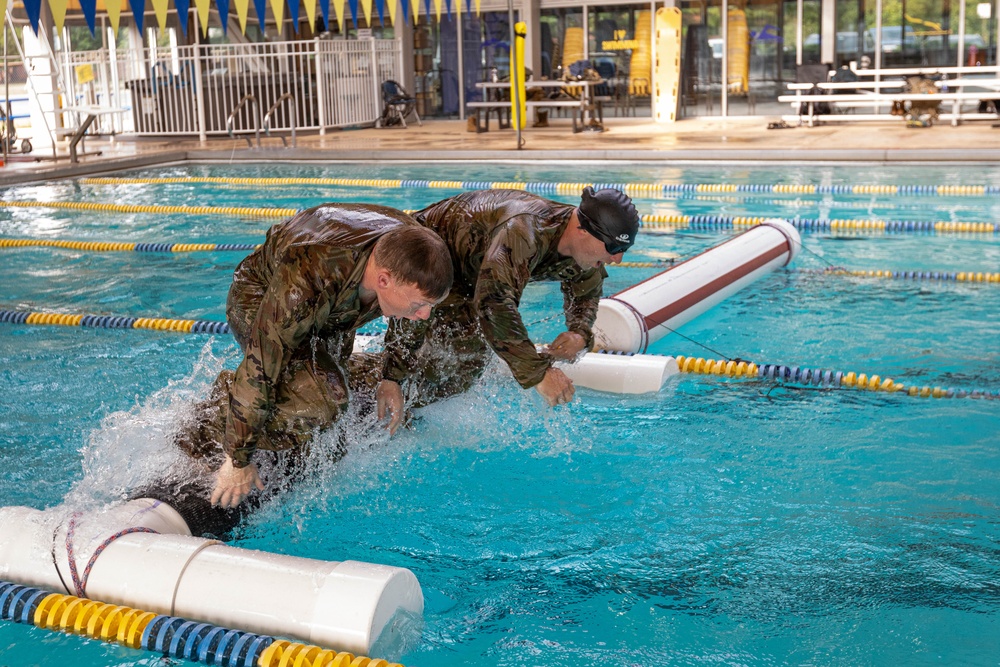 Sgt. Thomas Hunt and Sgt. 1st Class Benjamin Latham jump off of a water obstacle