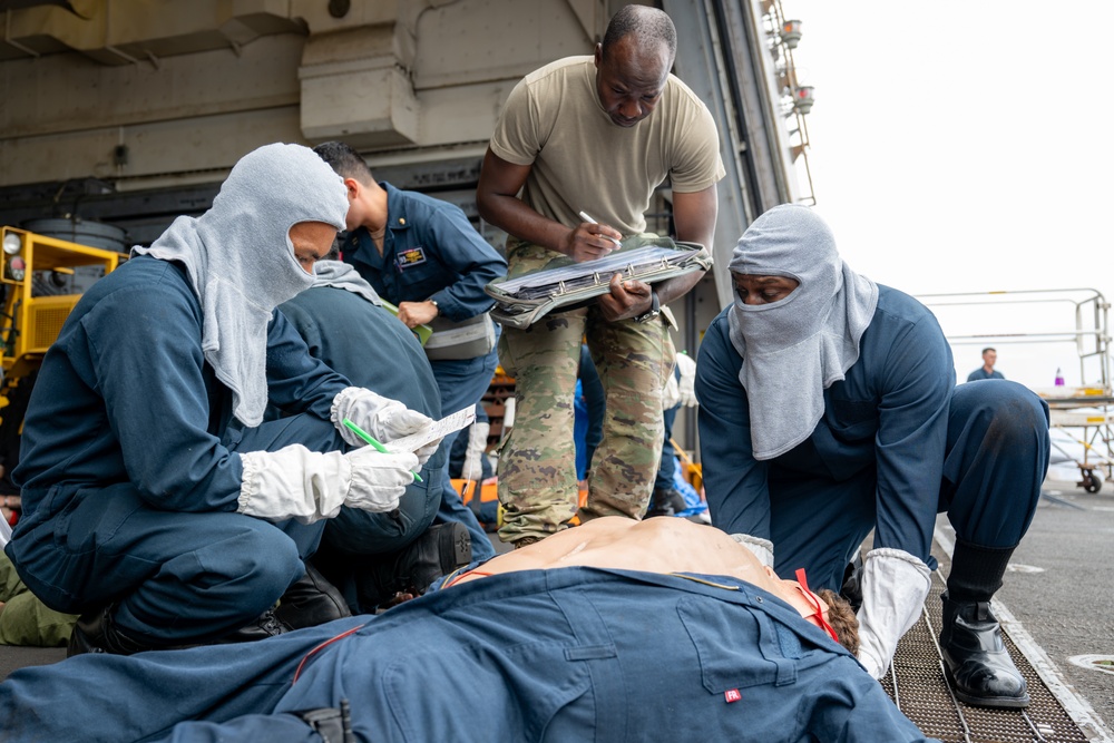 Navy Sailors and Army Soldier inspect patient during medical exercise