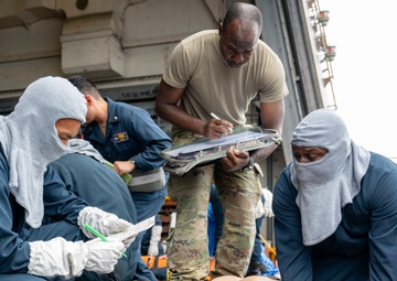 Navy Sailors and Army Soldier inspect patient during medical exercise