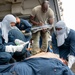 Navy Sailors and Army Soldier inspect patient during medical exercise