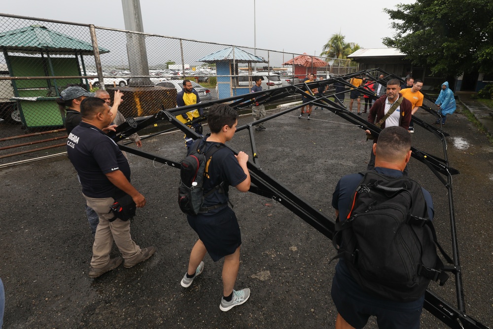 Sailors and Costa Rican medical professionals work side-by-side to build medical tents at the pier