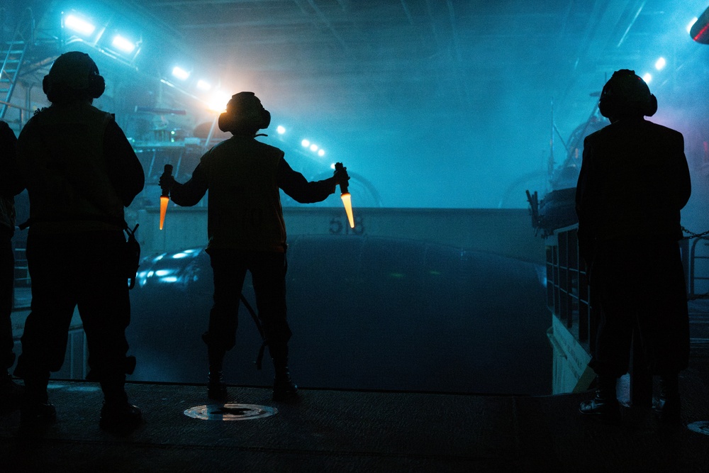 USS Somerset Boatswain’s Mate signals to LCAC during night operations