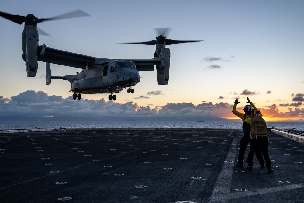 Airman signals to MV-22B Osprey during sunset