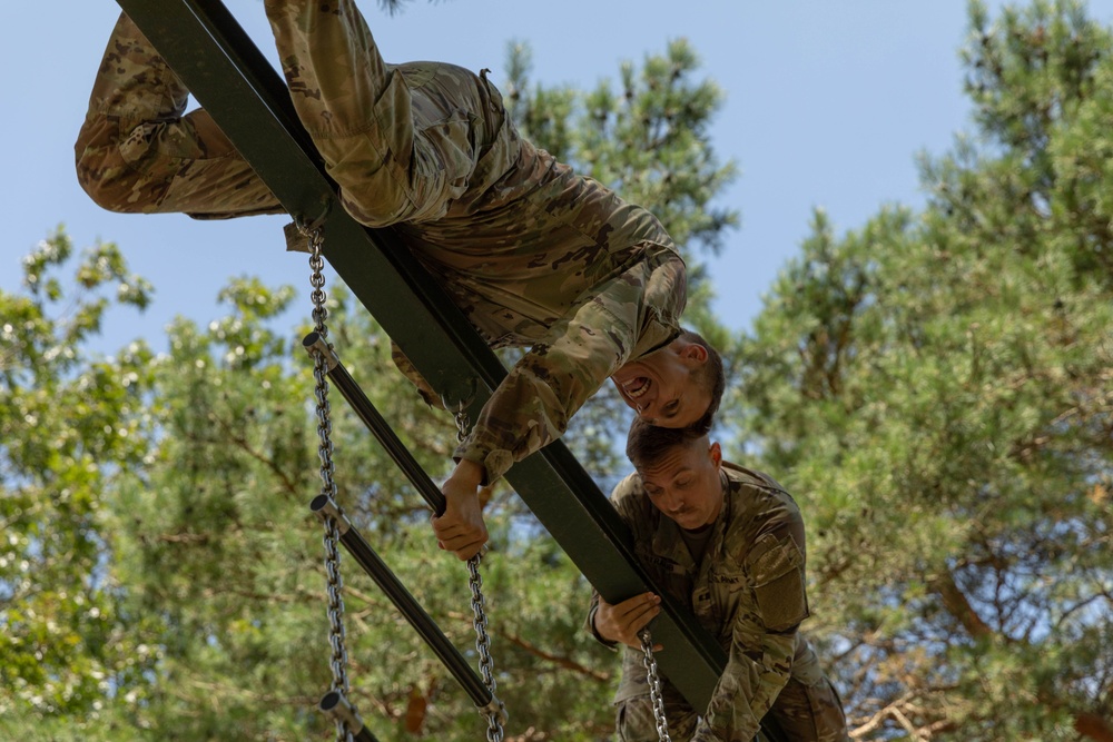 Two soldiers climb over an obstacle