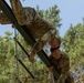 Two soldiers climb over an obstacle