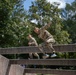 Two soldiers go over an obstacle