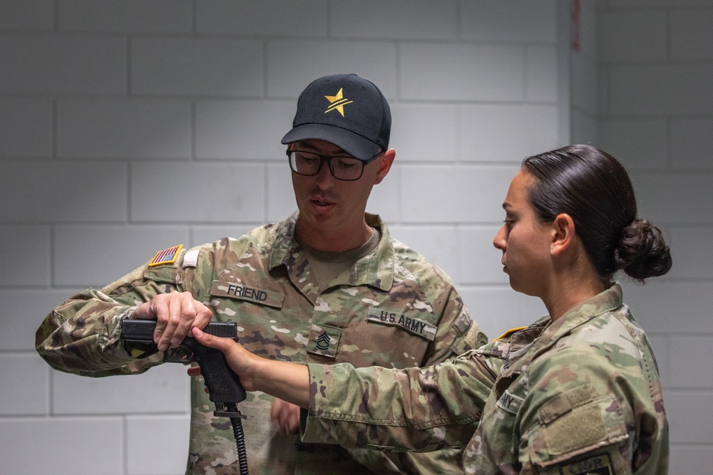 Sgt. 1st Class Kristoffer Friend instructs using a simulated weapon with 1st Lt. Brianna Mirmina