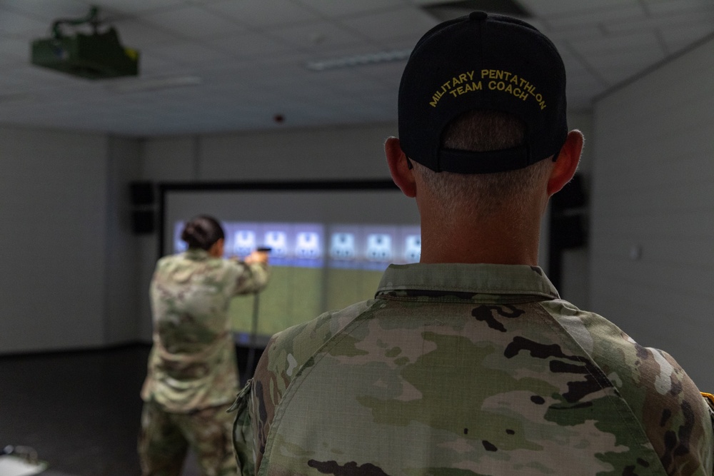 Sgt. 1st Class Kristoffer Friend watches 1st Lt. Brianna Mirmina fires a Glock 17 simulation pistol