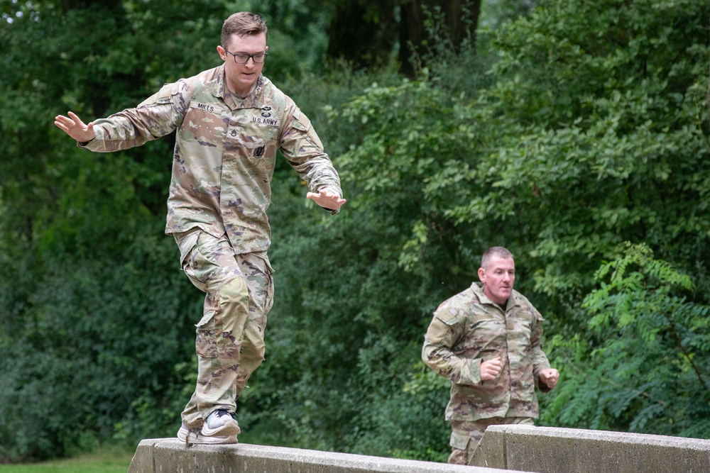 soldiers run across beams on obstacle course