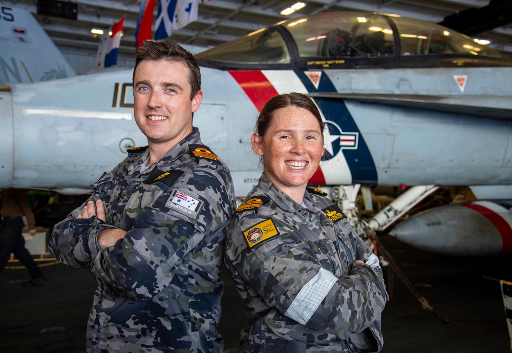 Lt. Cmdr. Eve Parker and Lt. Cmdr. Josh Goener, both assigned to the Royal Australian Navy, pose for a photograph after being promoted in rank in the hangar bay aboard Nimitz-class aircraft carrier USS Carl Vinson (CVN 70).