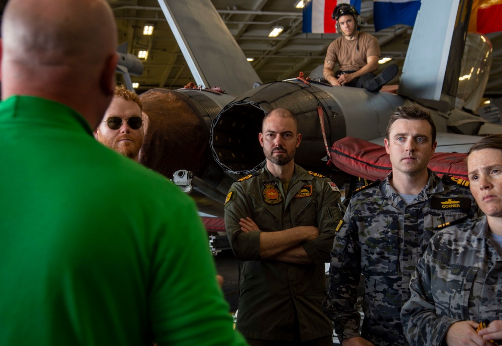 Partner nation military members tour the hangar bay aboard Nimitz-class aircraft carrier USS Carl Vinson (CVN 70).