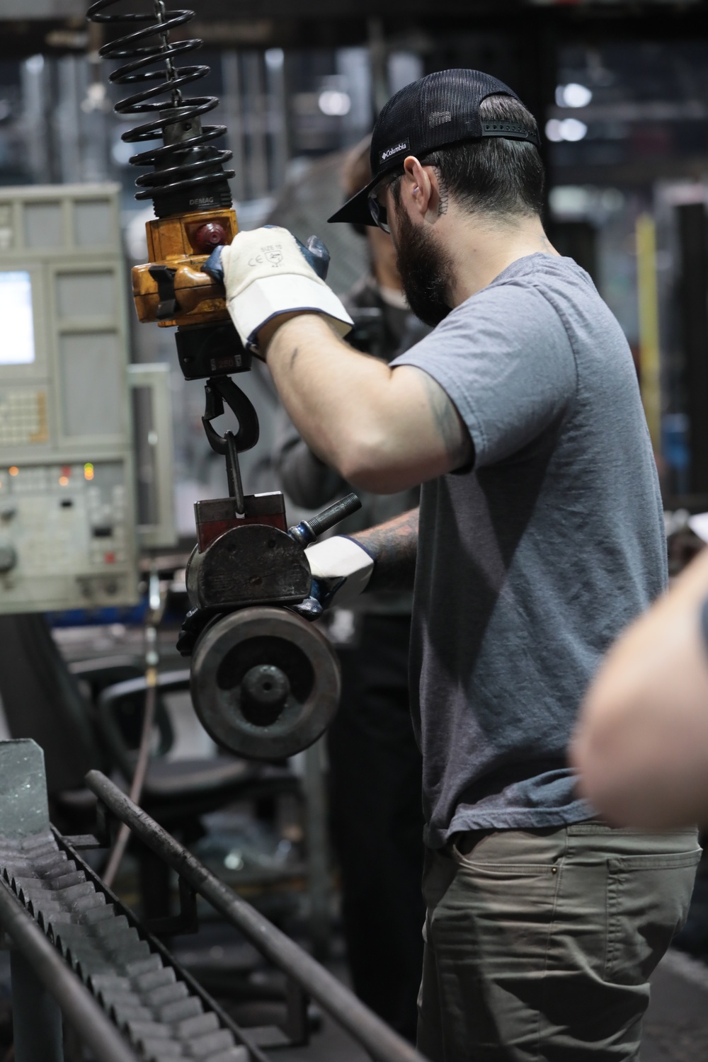 Employee at Scranton Army Ammunition Plant uses Automated Lifting System to Move Projectile Case off of the Conveyor to Start the Next Step in the Production Process