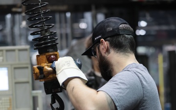 Employee at Scranton Army Ammunition Plant uses Automated Lifting System to Move Projectile Case off of the Conveyor to Start the Next Step in the Production Process