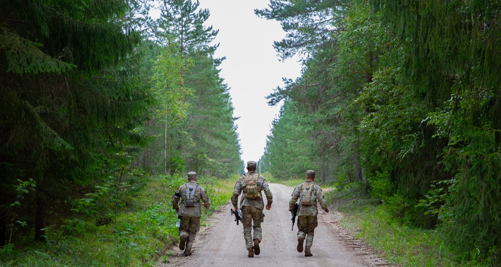 Service members negotiate terrain during a land navigation competition