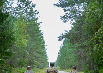 Service members negotiate terrain during a land navigation competition