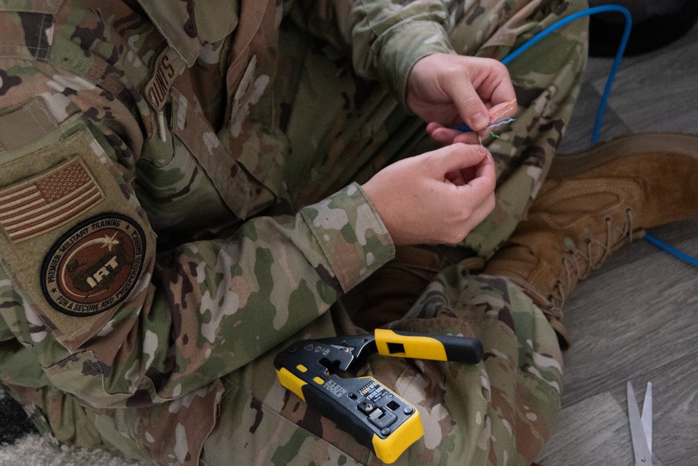 U.S. Air Force SrA Gavin Counts assists with running new wires and networks in a new Tribal Health IT building