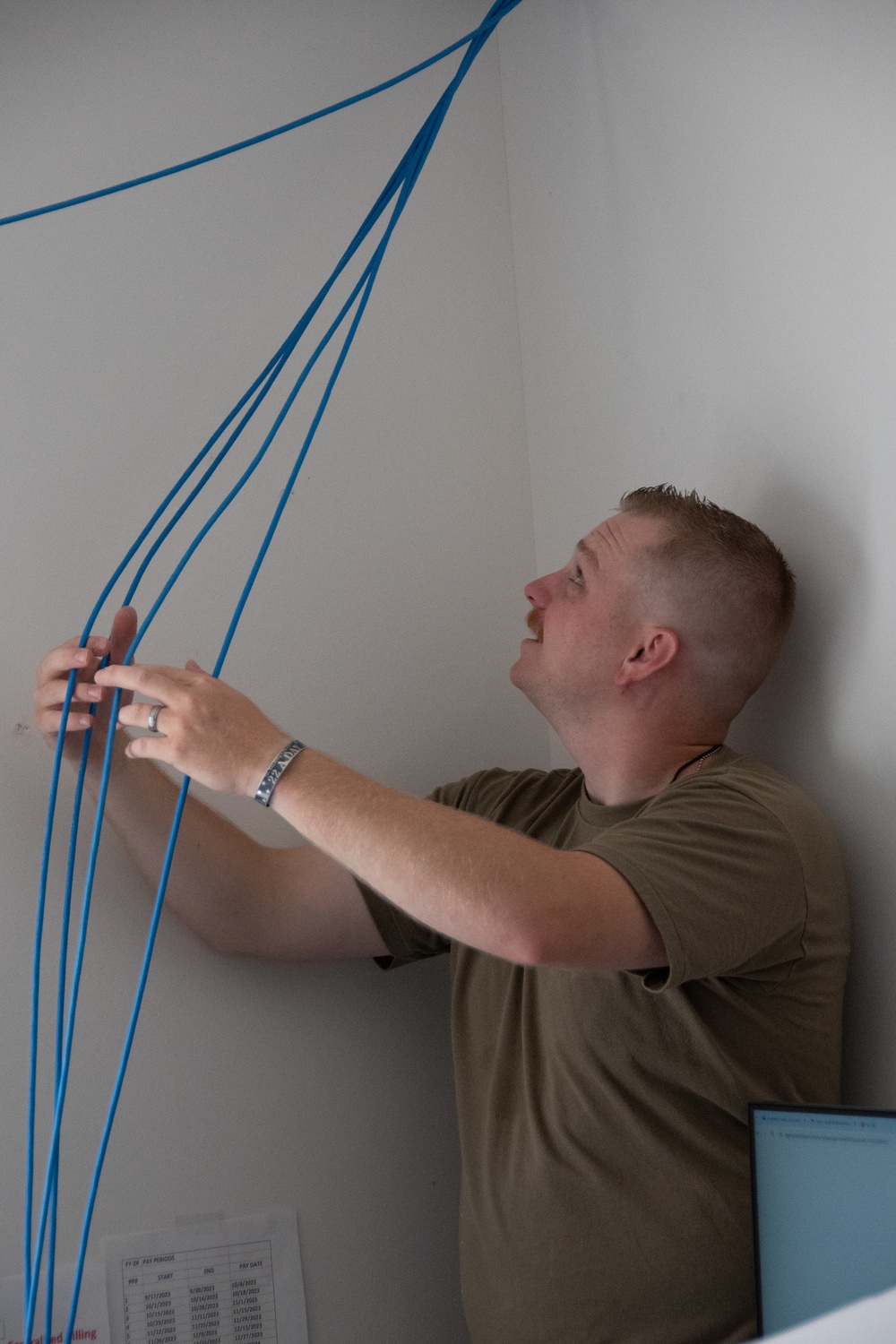 U.S. Air Force Staff Sgt. Braydon Dotson assists fellow service members in a rewiring project for the Blackfeet Tribal Health IT department