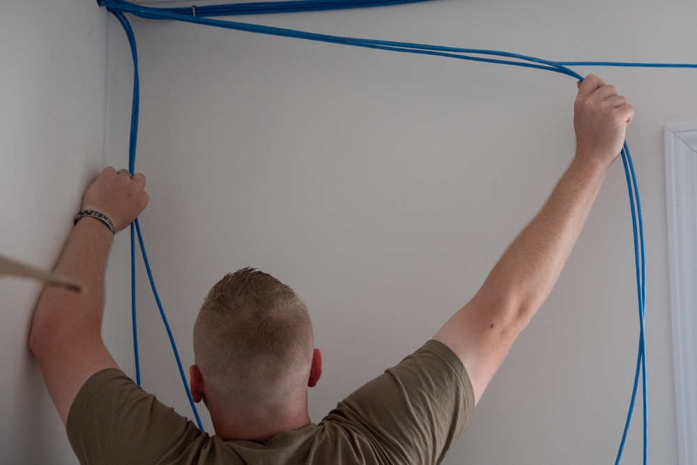 U.S. Air Force Staff Sgt. Braydon Dotson assists fellow service members in a rewiring project for the Blackfeet Tribal Health IT Department