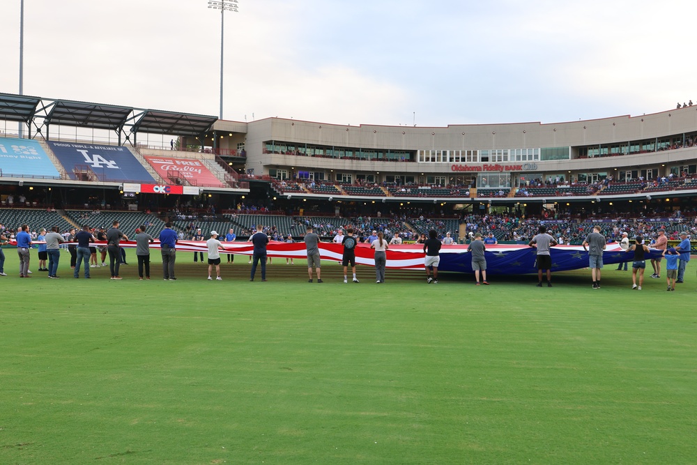 Volunteers hold American Flag during baseball game