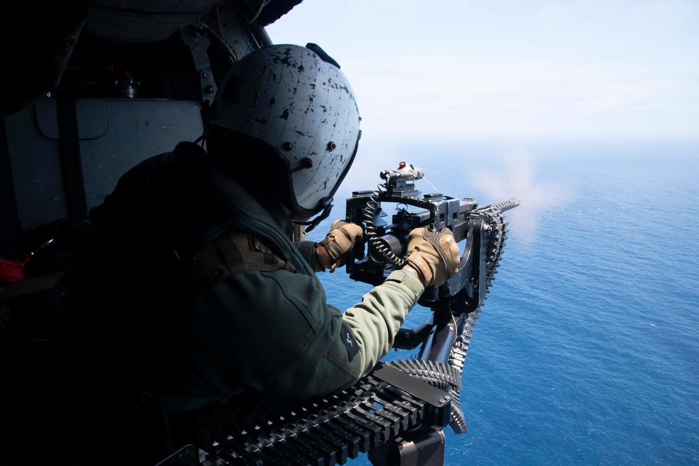 A Naval Air Crewman (Helicopter) fires an M3 .50 caliber machine gun