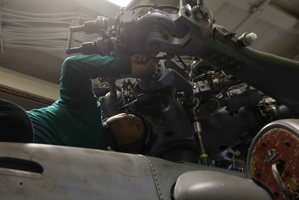 ATLANTIC OCEAN (Aug. 7, 2024) Aviation Machinist’s mate Airman William Laureano cleans and performs maintenance on a MH-60R helicopter in the hangar bay during Composite Training Unit Exercise (COMPTUEX)