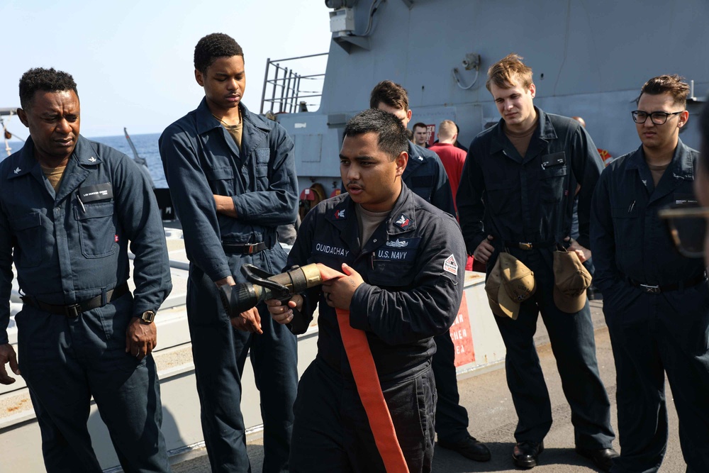 ATLANTIC OCEAN (Aug. 1, 2024) Damage Control Petty Officer 2nd Class Nicolas Quidachay teaches a Damage Control Academy class how to handle a firefighting hose during Composite Training Unit Exercise (COMPTUEX)