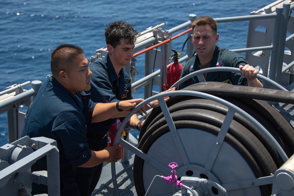 USS Tripoli Sailors spray and clean AFFF off of the Flight deck