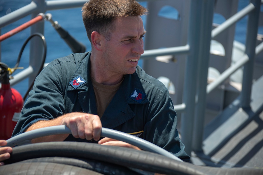 USS Tripoli Sailors spray and clean AFFF off of the Flight deck
