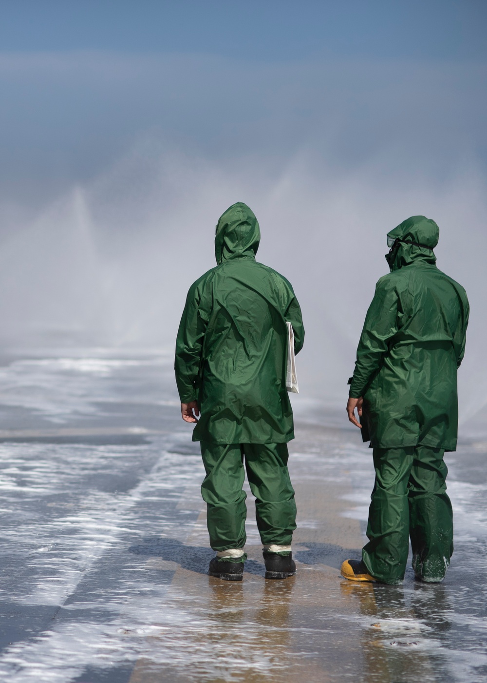 USS Tripoli Sailors spray and clean AFFF off of the Flight deck