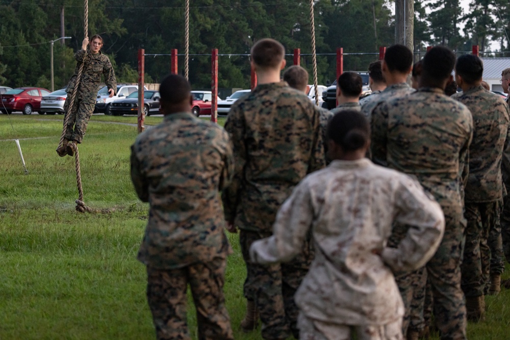 Marines with Marine Corps Combat Service Support Schools maneuver through an obstacle course