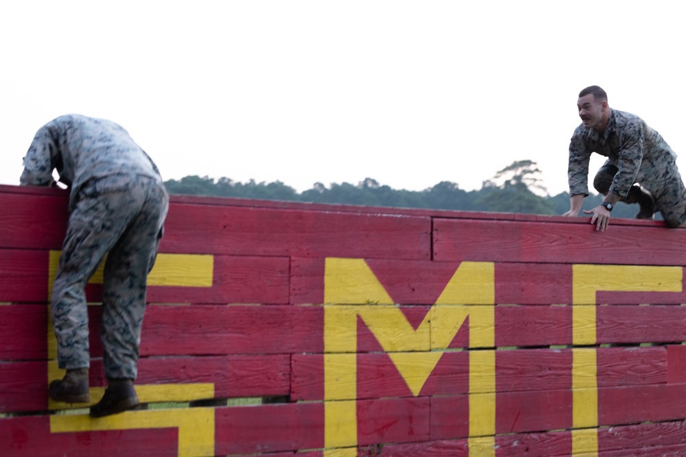 Marines with Marine Corps Combat Service Support Schools maneuver through an obstacle course