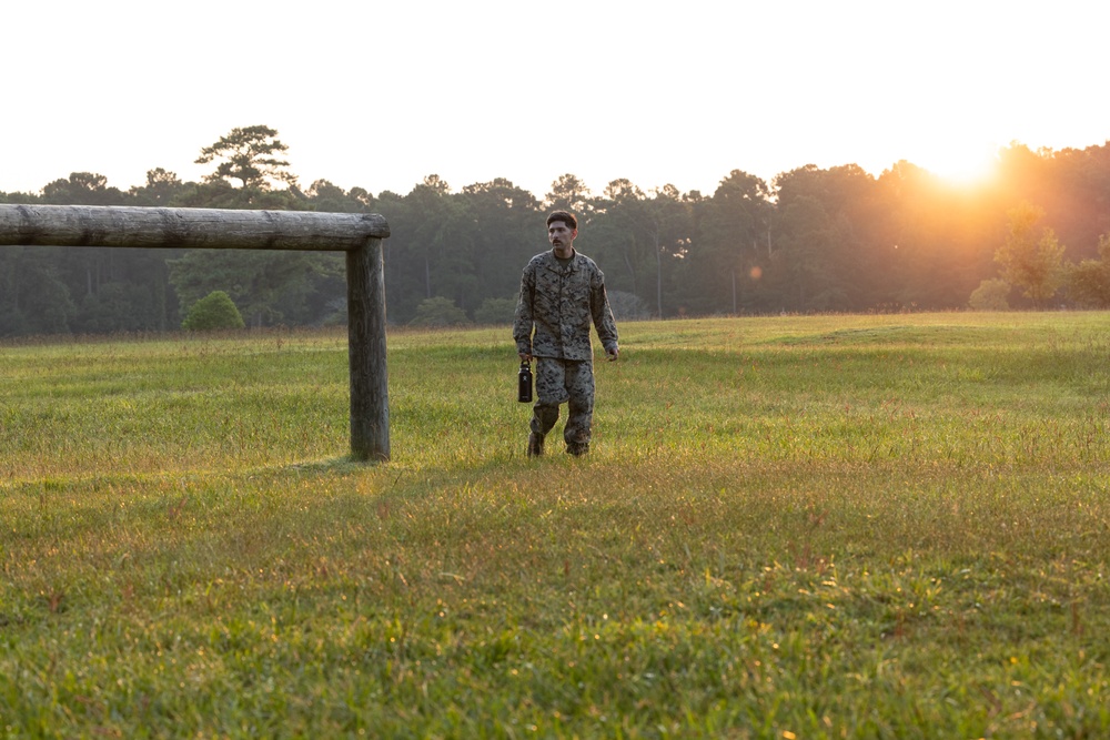 Marines with Marine Corps Combat Service Support Schools maneuver through an obstacle course