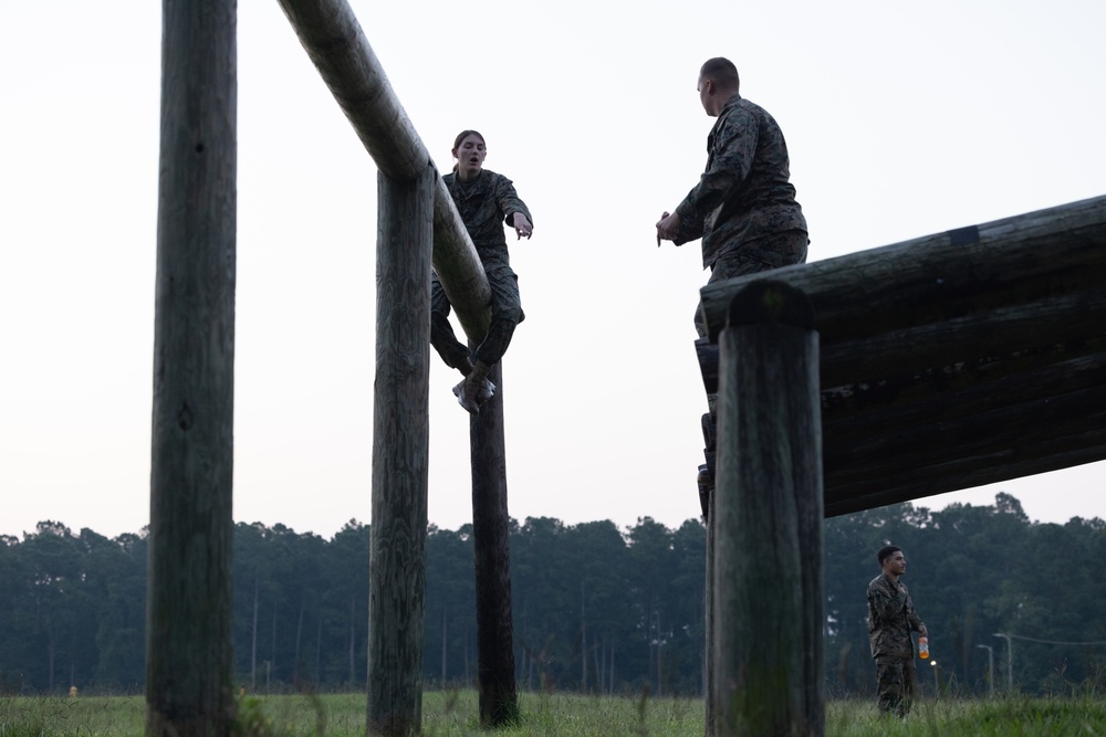 Marines with Marine Corps Combat Service Support Schools maneuver through an obstacle course