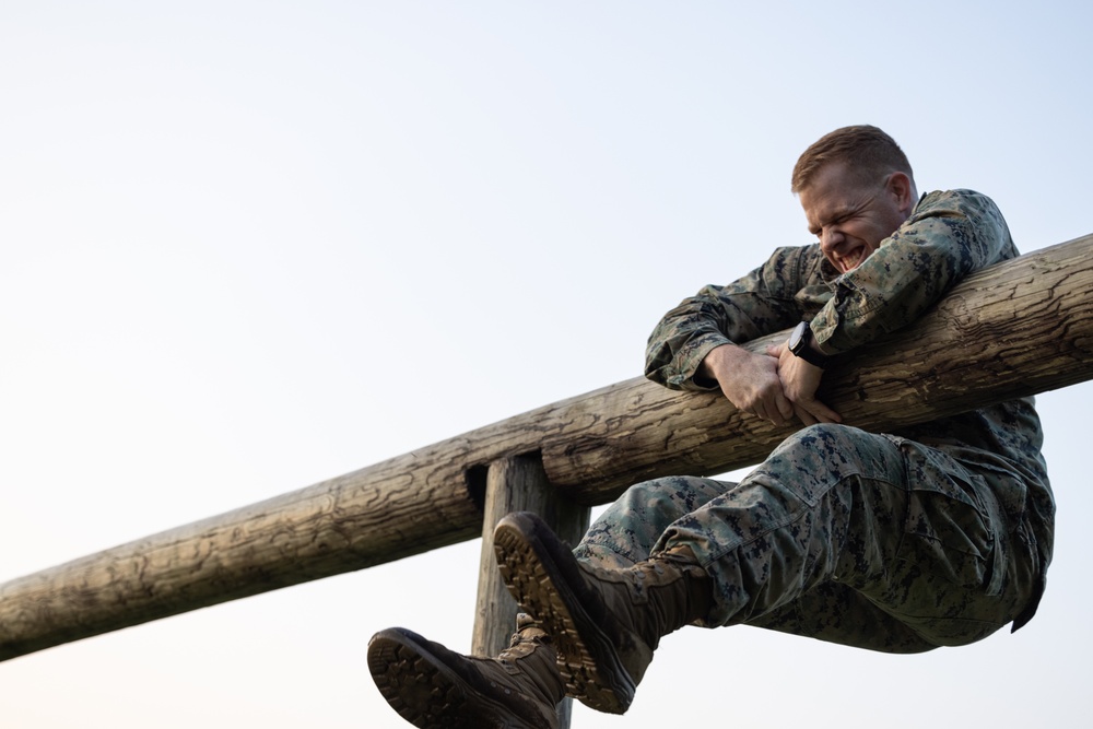 Marines with Marine Corps Combat Service Support Schools maneuver through an obstacle course