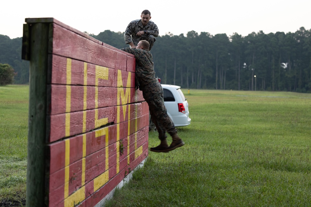 Marines with Marine Corps Combat Service Support Schools maneuver through an obstacle course