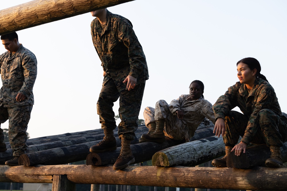 Marines with Marine Corps Combat Service Support Schools maneuver through an obstacle course