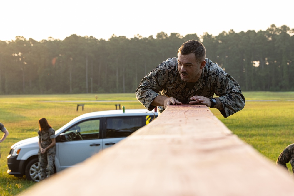 Marines with Marine Corps Combat Service Support Schools maneuver through an obstacle course