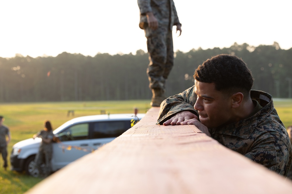 Marines with Marine Corps Combat Service Support Schools maneuver through an obstacle course