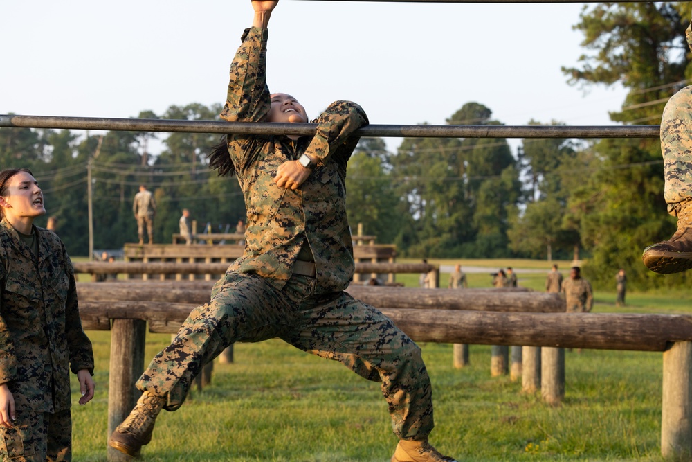 Marines with Marine Corps Combat Service Support Schools maneuver through an obstacle course