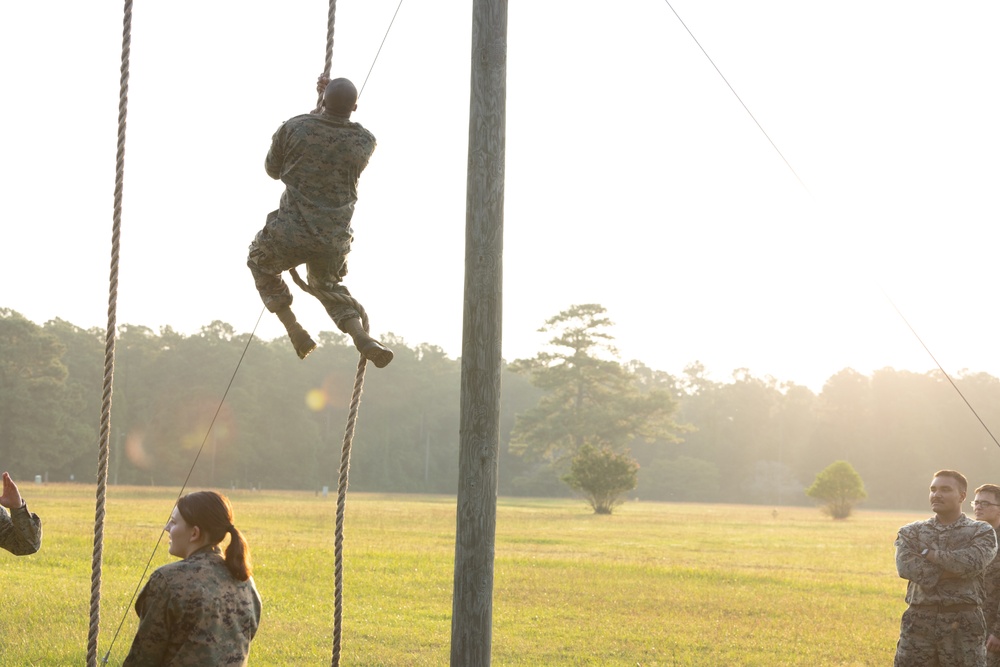 Marines with Marine Corps Combat Service Support Schools maneuver through an obstacle course