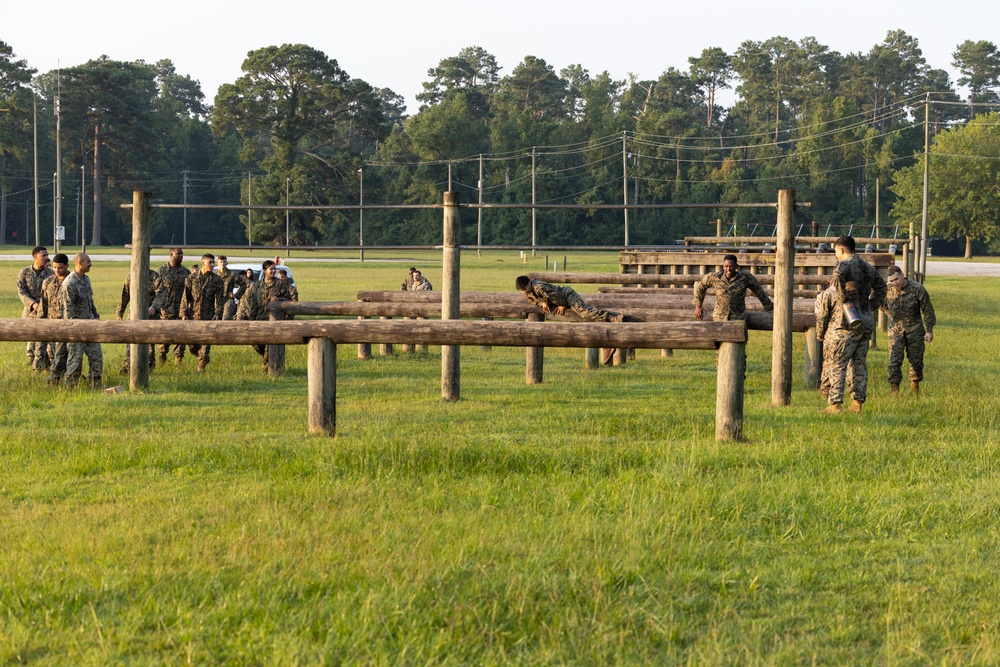 Marines with Marine Corps Combat Service Support Schools maneuver through an obstacle course