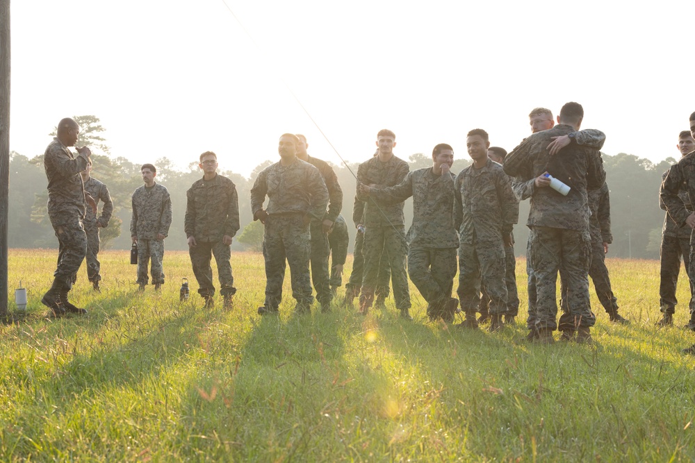 Marines with Marine Corps Combat Service Support Schools maneuver through an obstacle course